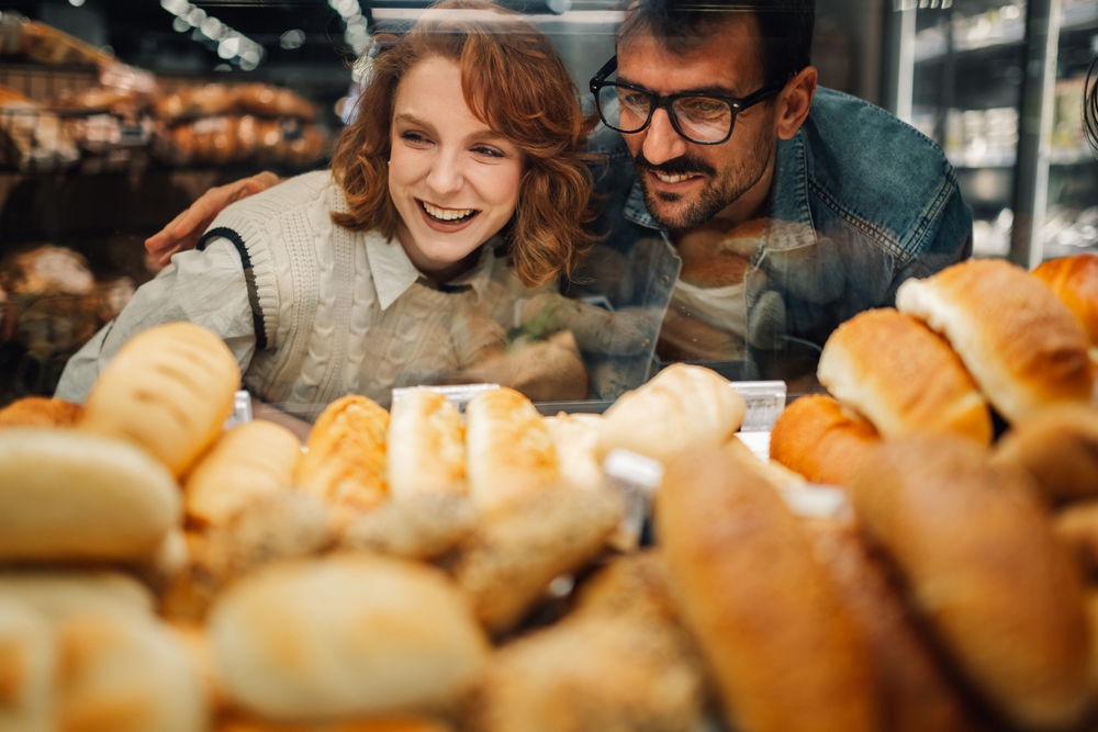 Smiling,Man,And,Woman,Choosing,Fresh,Bread,From,A,Bakery